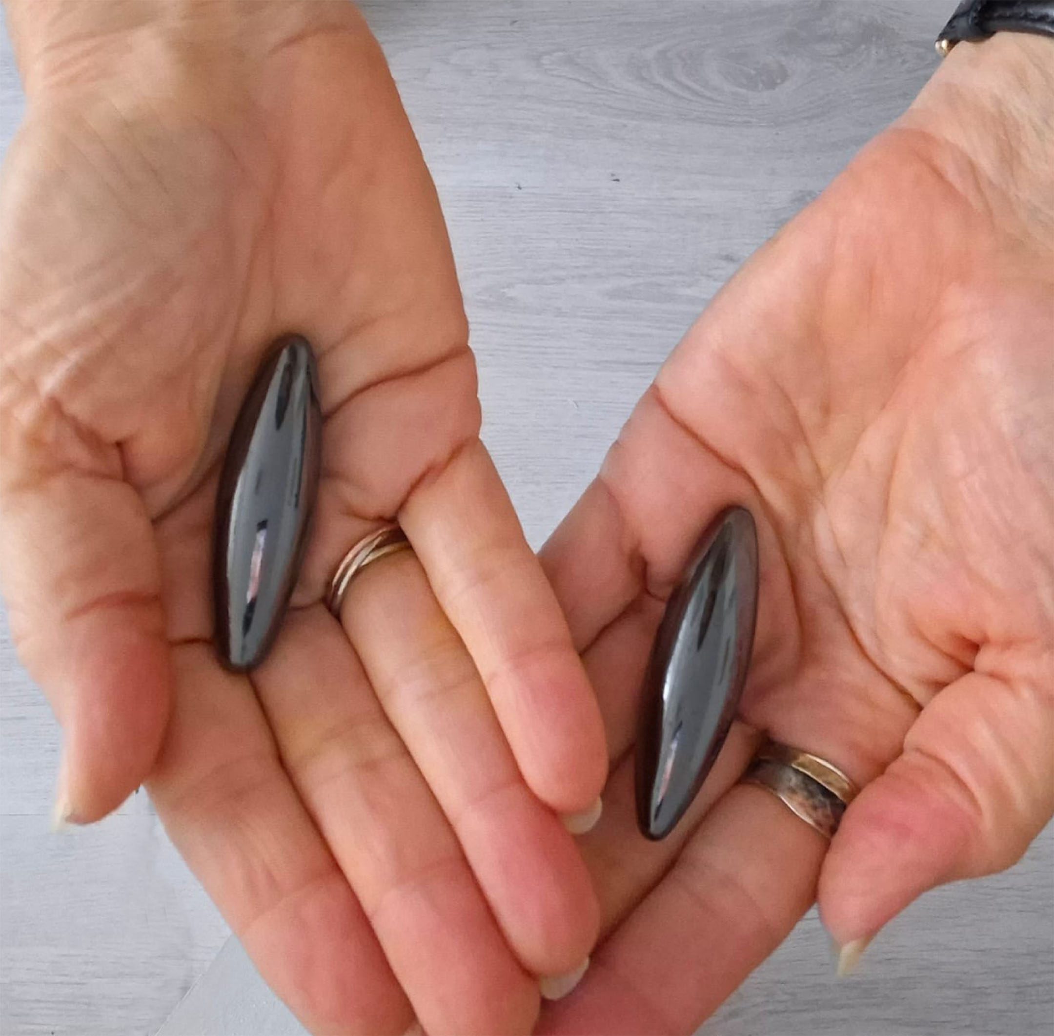 Magneet therapie set van Hematiet en Magnetiet in twee open handen, ter visualisatie van formaat en energetisch gebruik